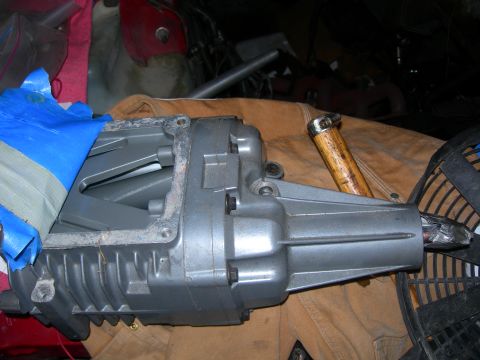 1984 Ford Bronco - A gray supercharger part is shown, covered partially with blue tape, with a hammer handle nearby.