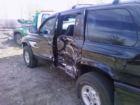 1972 Ford Ranchero - A black Dodge Durango SUV photographed from the driver's side showing severe collision damage, with both doors and the rocker panel crushed…