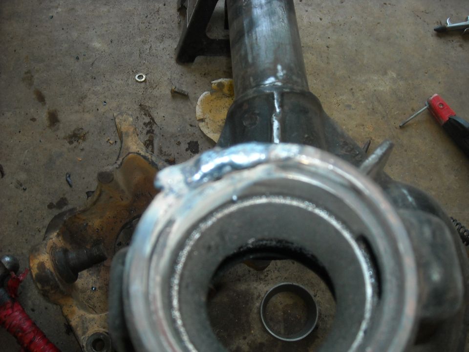 Photo of a welded axle shaft and housing end on a garage floor