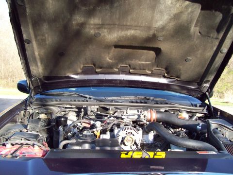 1999 Mercury Grand Marquis - The open hood of a dark colored sedan reveals a detailed view of the engine bay, featuring an aftermarket cold air intake system and a yell…