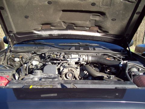 1999 Mercury Grand Marquis - The engine bay of a dark-colored Mercury Grand Marquis is shown with the hood open, revealing the V8 engine, air intake system, and various…