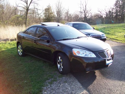 1999 Mercury Grand Marquis - A black four-door sedan is parked on a grassy area next to a gravel driveway. Another dark-colored sedan is parked behind it.