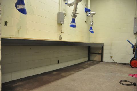 1996 Ford Bronco - Photograph of articulated fume-extraction arms over an empty workbench in a shop.