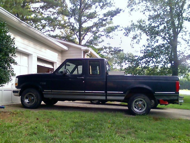 Dark blue Ford F-150 pickup truck parked next to a house.