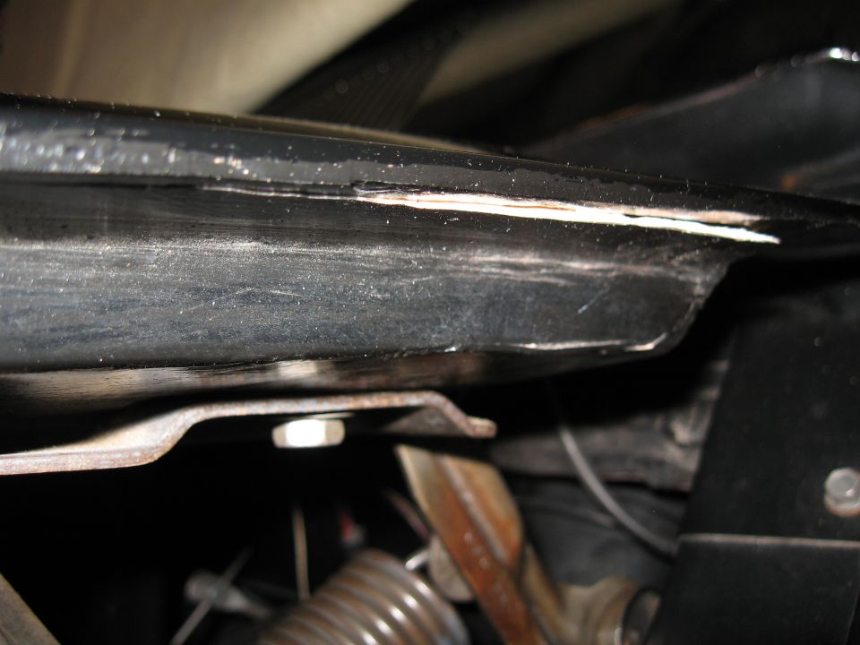 Close-up of black metal component with white damage, and a silver bolt.