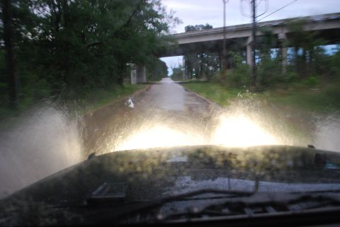 2008 Jeep Wrangler - View from inside a vehicle driving through a flooded road with headlights on, creating large splashes. An overpass is visible in the distan…