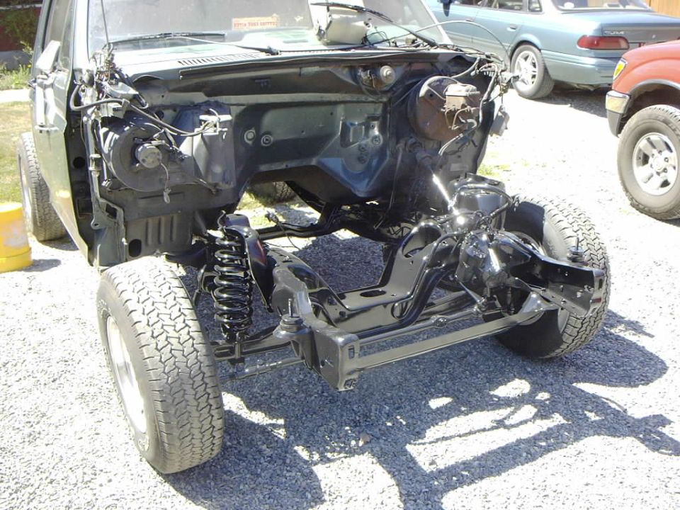 Truck chassis with engine and suspension exposed, front end stripped