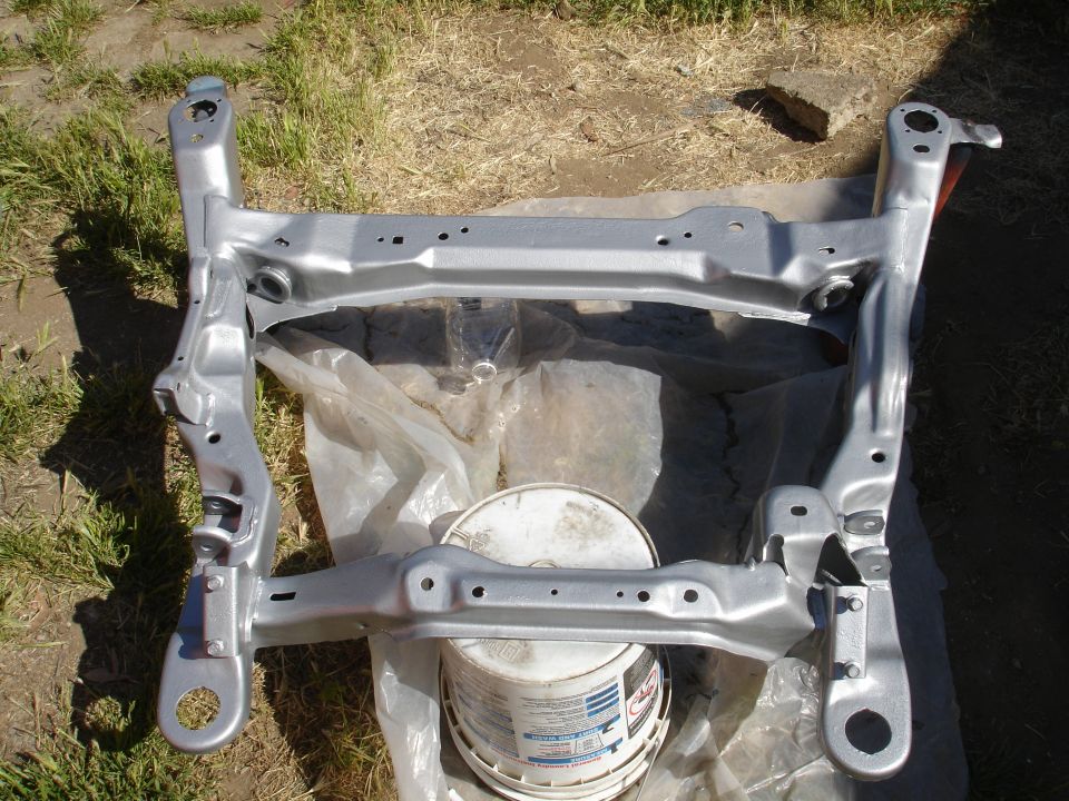 Photo of a silver engine subframe crossmember lying on the ground