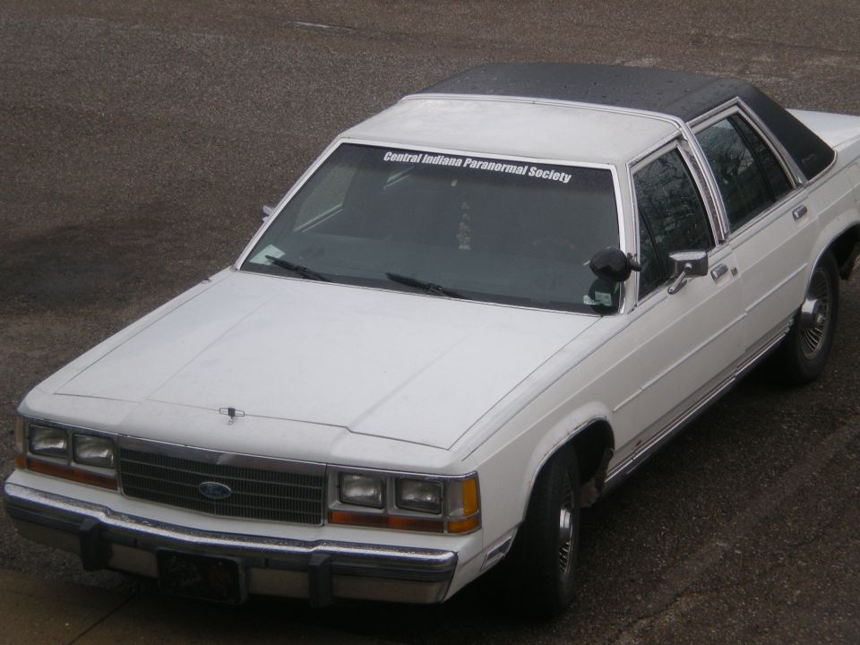 White Ford full-size sedan with black vinyl roof and Central Indiana Paranormal Society windshield banner