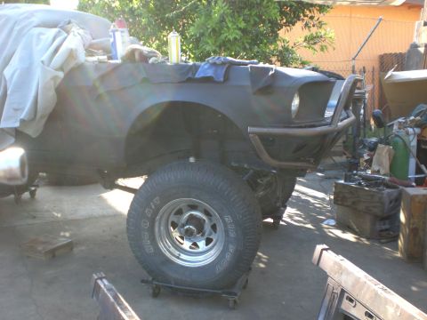 1967 Ford Mustang - A heavily modified vehicle, possibly a Ford Mustang, is shown from a low front 3/4 angle. The vehicle features a custom roll cage/bumper an…