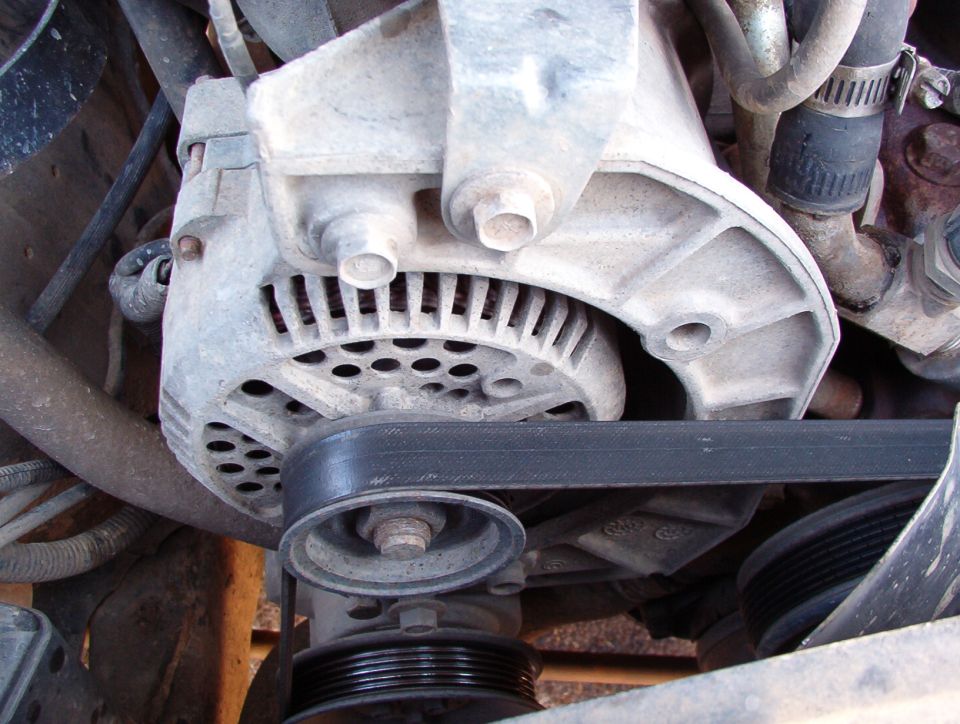 Engine bay alternator mounted on aluminum bracket driven by serpentine belt and pulley
