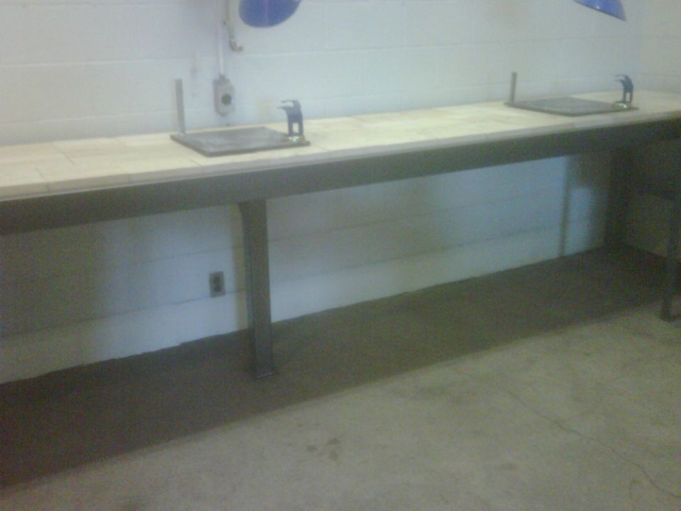 Long tiled lab bench with two stainless sinks against a block wall