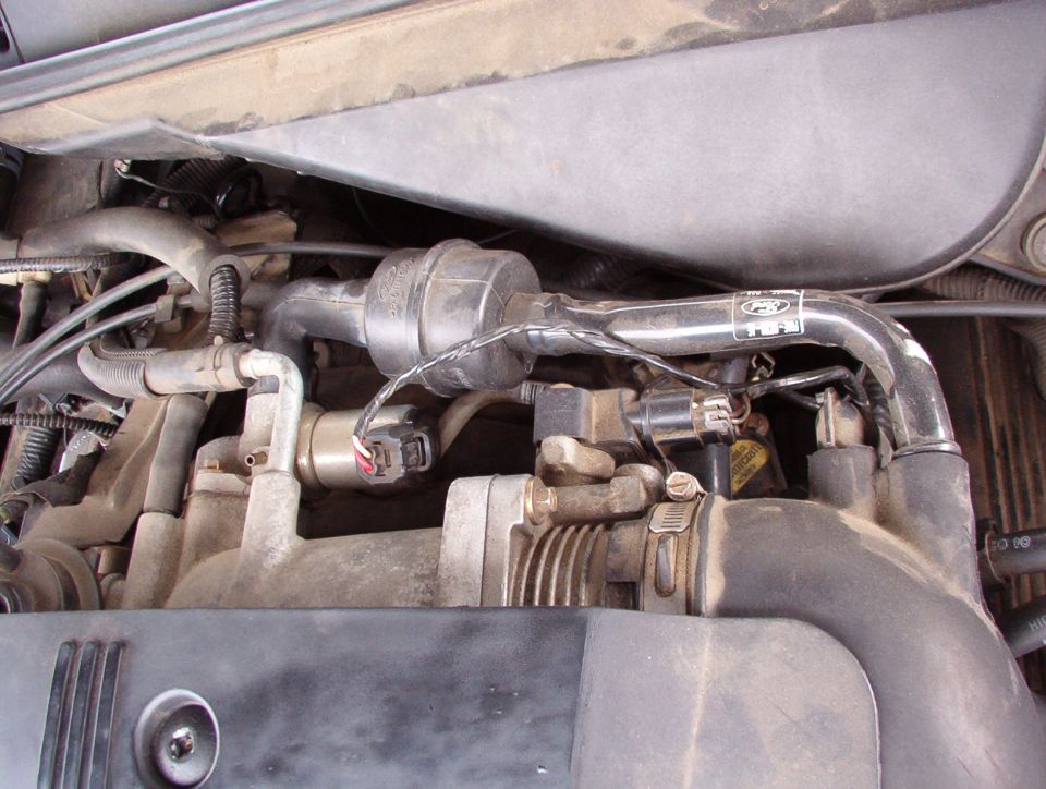 Dusty engine bay showing canister, wiring connector and metal coolant lines