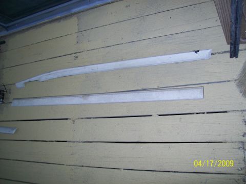 1972 Ford Ranchero - Two pieces of light-colored trim are laid out on a weathered, pale yellow wooden deck. The trim pieces appear to be automotive body trim.