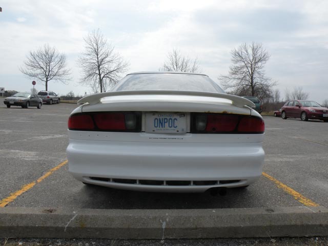 Rear view of a white 1995 Ford Probe with a spoiler and license plate ONPOC.