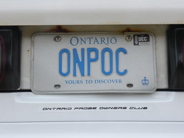 Ontario license plate ONPOC on a white car, with a rust stain above it and an Ontario Probe Owners Club sticker below.