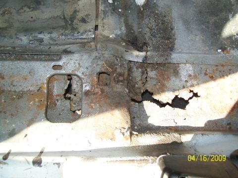 1972 Ford Ranchero - The image shows severe rust and holes in the metal floor pan of a vehicle, likely from the underside. The rust is orange-brown and flaky, w…