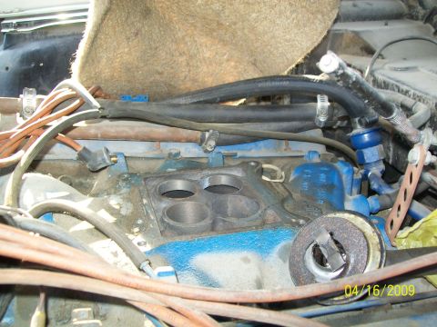 1972 Ford Ranchero - Close-up view of a V8 engine's intake manifold and carburetor area, with various hoses, wires, and a blue fuel regulator visible. The engin…