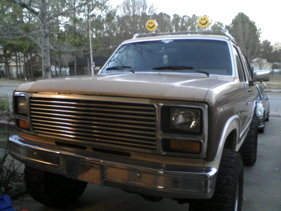 Tan SUV with smiley face lights on roof, 3/4 front view
