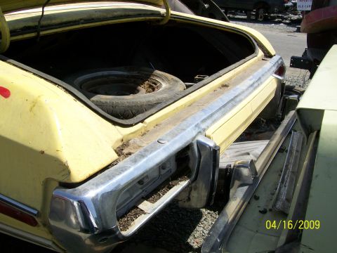 1972 Ford Ranchero - The rear of a yellow 1972 Ford Ranchero is visible, with its trunk open and a spare tire inside.