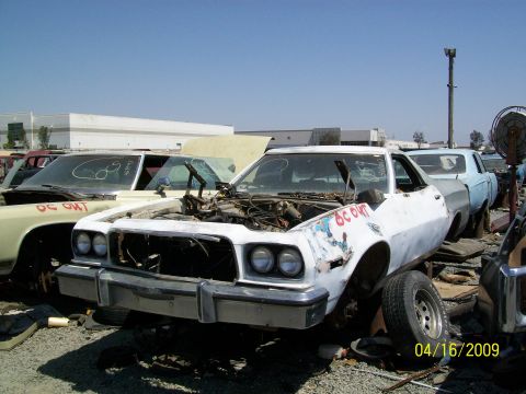 1972 Ford Ranchero - This 1975 Ford Ranchero sits in a junkyard with its hood open, showing the engine compartment.
