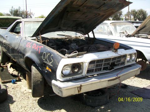1972 Ford Ranchero - A 1972 Ford Ranchero sits in a parts yard with its hood open, revealing the engine and OCS markings on the fender.