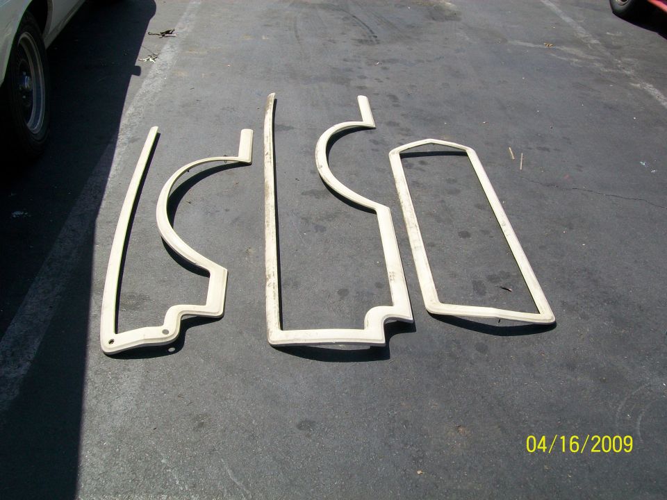 Four beige weatherstripping pieces laid out on asphalt