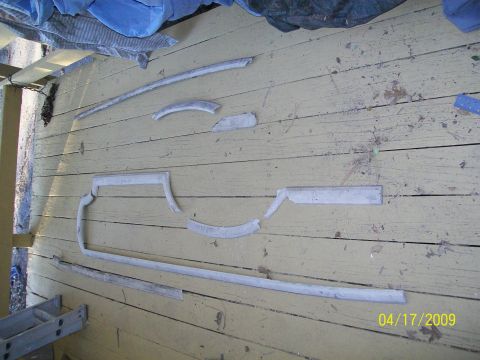 1972 Ford Ranchero - Several pieces of car trim are arranged on a weathered wooden surface, possibly for restoration or inventory.