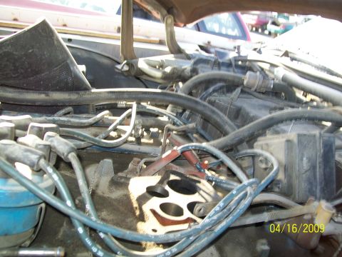 1972 Ford Ranchero - The engine bay of a vehicle is shown, with various hoses and spark plug wires in focus.