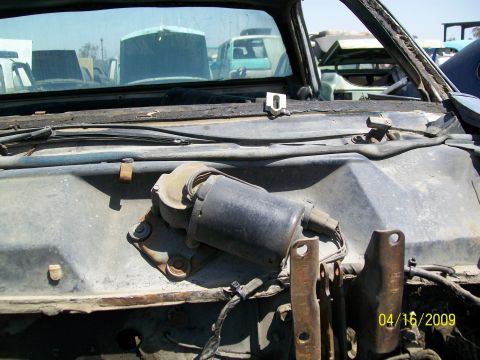 1972 Ford Ranchero - A close-up of a windshield wiper motor assembly is visible, with other vehicles in a junkyard setting.