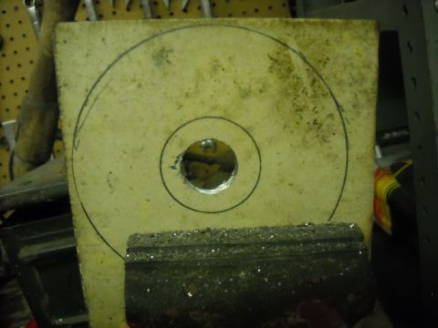 1979 Ford F-150 - A part with concentric circles and a hole, clamped in a vise, ready for work.