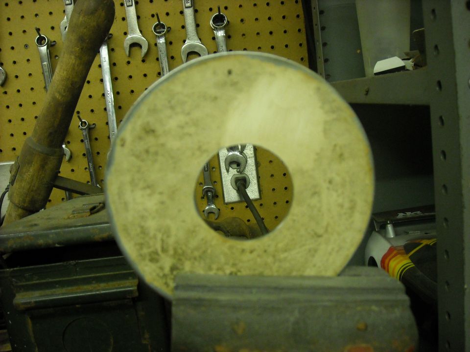 Workbench with tools on pegboard, a grinding wheel in foreground, and a white toy car in background