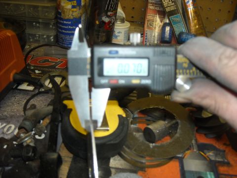 1979 Ford F-150 - A digital caliper is used to measure a small metal component, with a cluttered workbench visible.