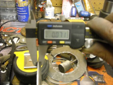 1979 Ford F-150 - A digital caliper is used to measure the thickness of a metal washer on a workbench.