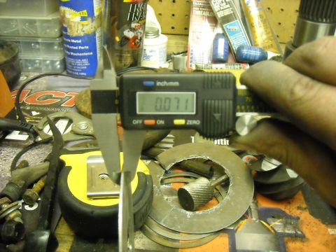 1979 Ford F-150 - A digital caliper is used to measure a metal component, surrounded by various tools and automotive parts.