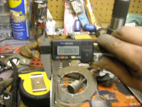 1979 Ford F-150 - A digital caliper measures a metal part to 0.069 inches, with various tools and cans in the background.