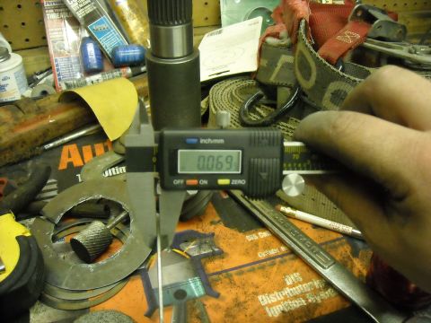 1979 Ford F-150 - Measuring a part with a digital caliper on a cluttered workbench.