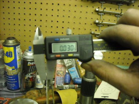 1979 Ford F-150 - A digital caliper measures a splined shaft, with various automotive parts and tools visible on a workbench.