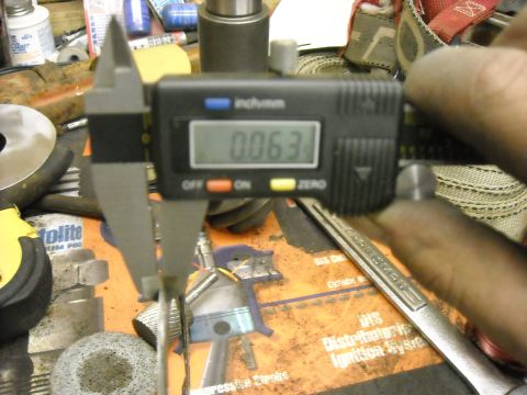 1979 Ford F-150 - Digital caliper measuring a part to 0.063 inches. Background shows various tools and workshop items.