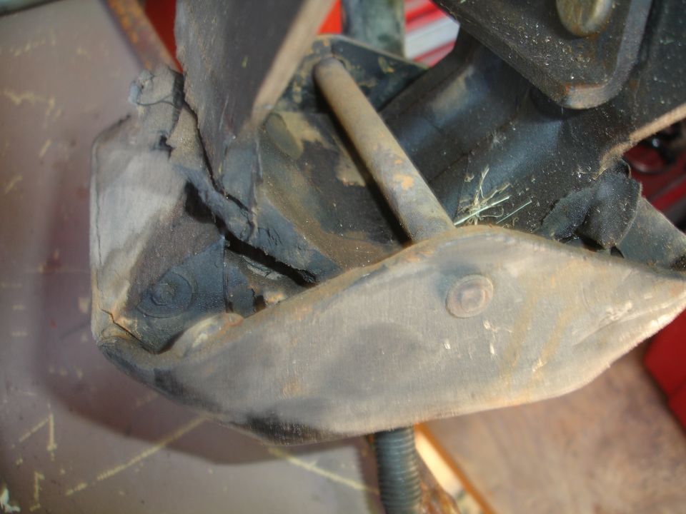Close-up of a cracked and worn engine mount with a metal rod passing through it