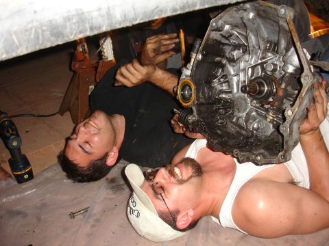 1995 Ford Taurus - Mechanics work on a car's transmission, which is held by one of the men.