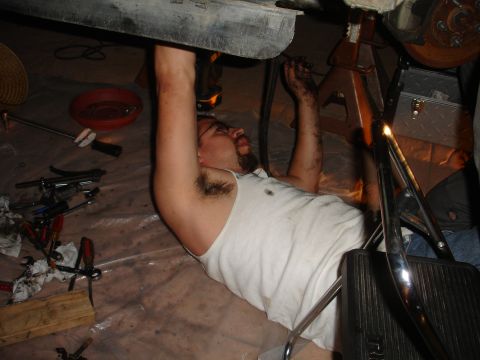 1995 Ford Taurus - Man performs maintenance on a vehicle's undercarriage with tools laid out nearby.