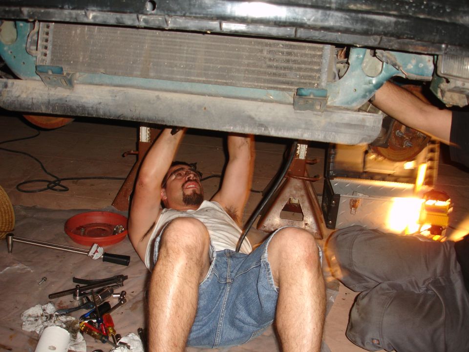Guy working under car on jack stands, tools scattered around