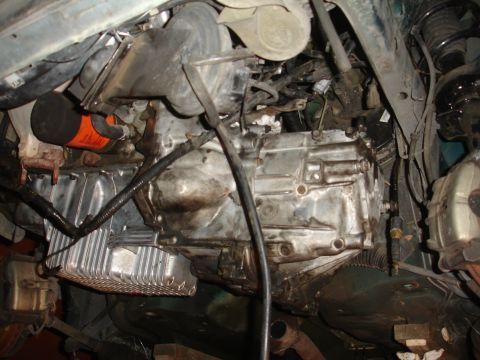 1995 Ford Taurus - Underside view of a vehicle's transmission and oil pan, with an orange oil filter attached.