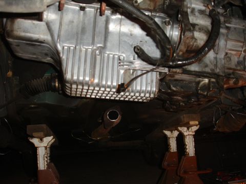 1995 Ford Taurus - Underside view of a vehicle's engine compartment, showing the oil pan and exhaust system supported by jack stands.