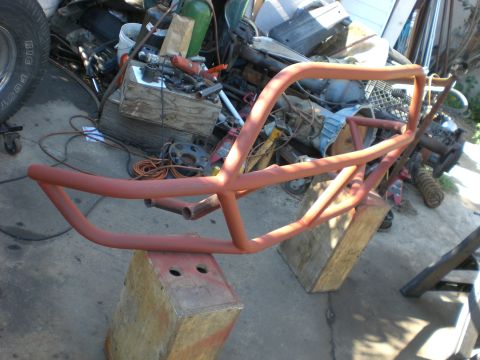 1967 Ford Mustang - A custom front bumper assembly, painted red, is shown mounted on wooden blocks in a workshop setting.