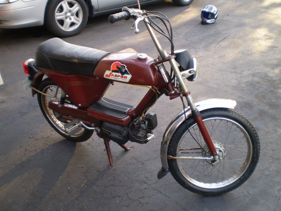 Maroon Garelli moped in a driveway with Jasper decal on the tank and spoked wheels