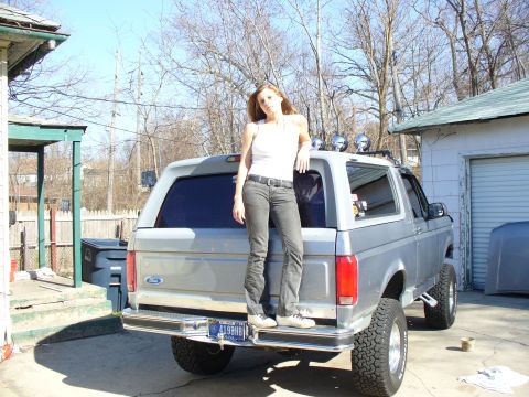 1994 Ford Bronco - Woman poses on the tailgate of a 1994 Ford Bronco parked in a driveway.