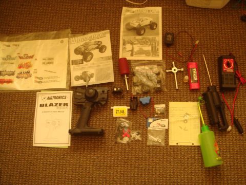 1992 Ford Bronco - Collection of RC car components including a remote, batteries, tools, and instruction manuals.