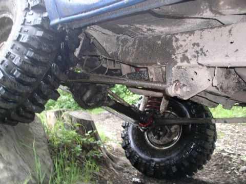 1979 Ford Bronco - The underside of a heavily modified off-road vehicle is shown, with large tires and suspension components visible.